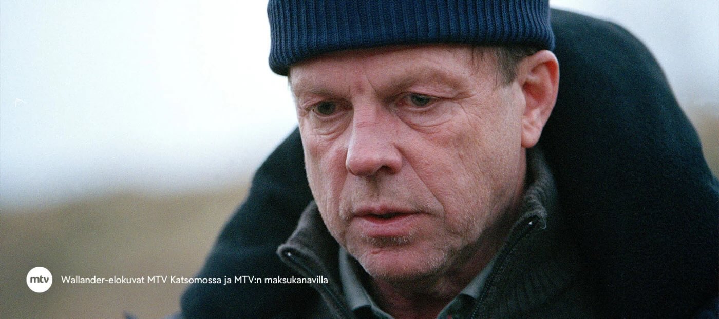 Lähikuva henkilöstä ulkovaatteissa ja neulospipo päässä ulkoilmassa. Kuva on Wallander-elokuvasarjasta.