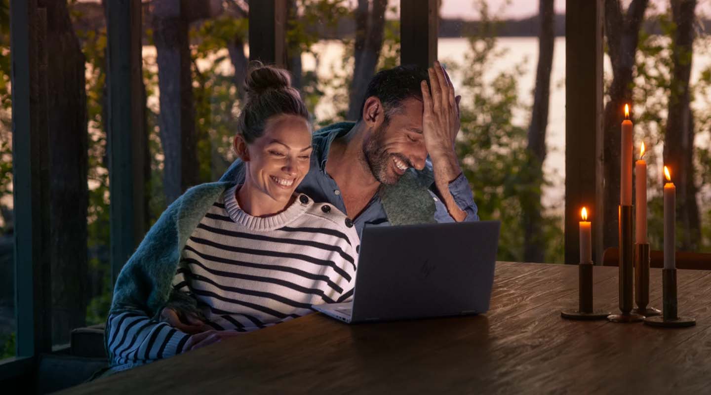 Nainen ja mies tietokoneella mökkiterassilla