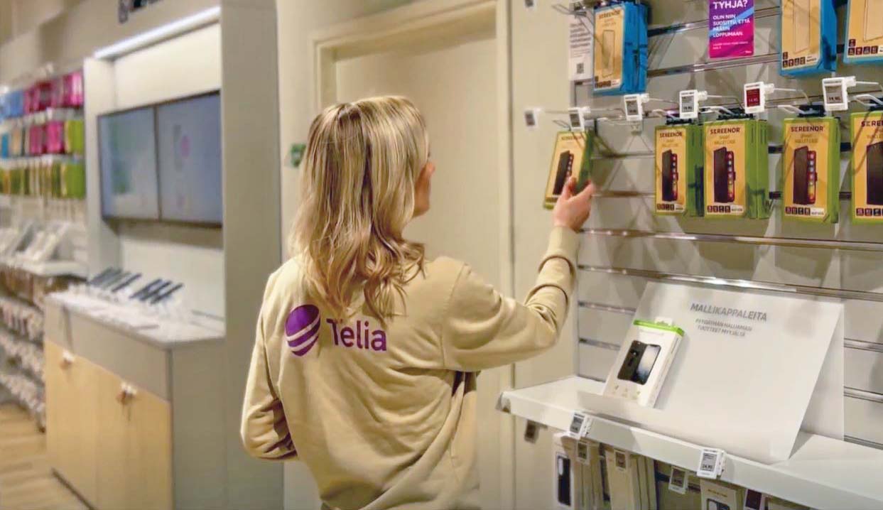 Sales Agent Elina hyllyttämässä puhelimenkuoria Telia Kaupassa.