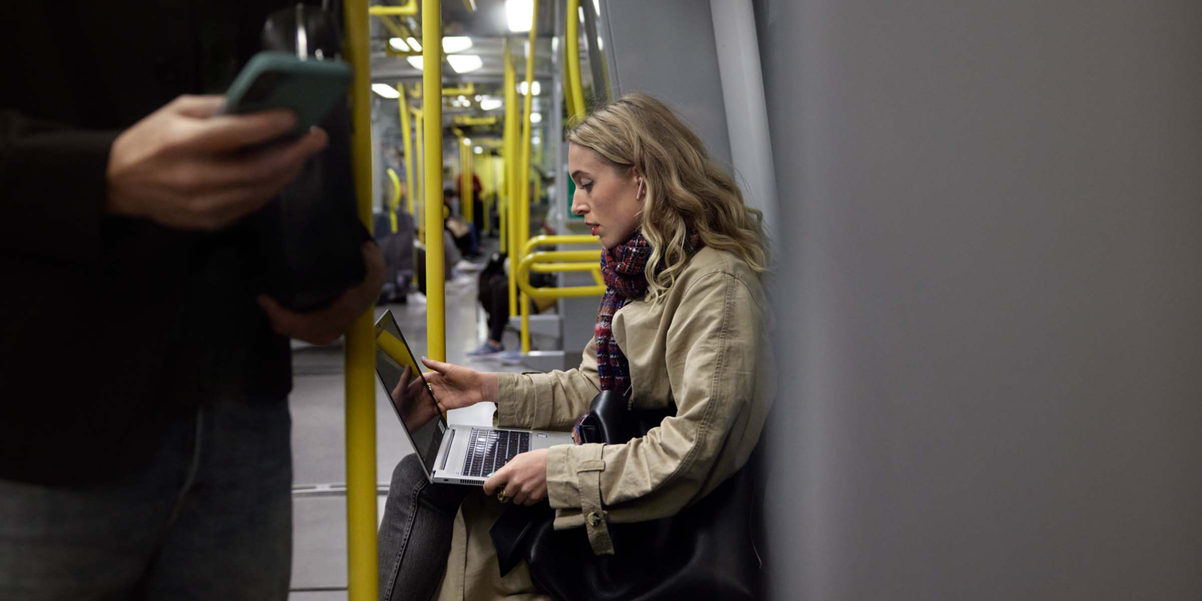 Nainen istuu läppärin kanssa junassa avoimeen wi-fi-verkkoon liittyneenä. 