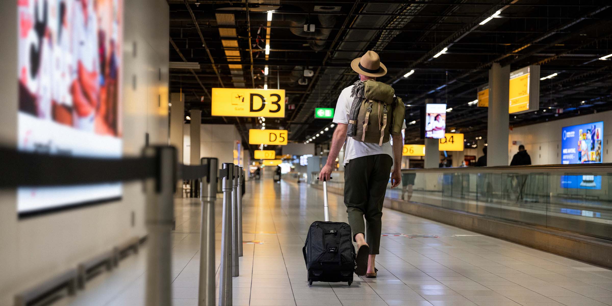 Mies kävelee junalaiturilla ja vetää matkalaukkua perässä